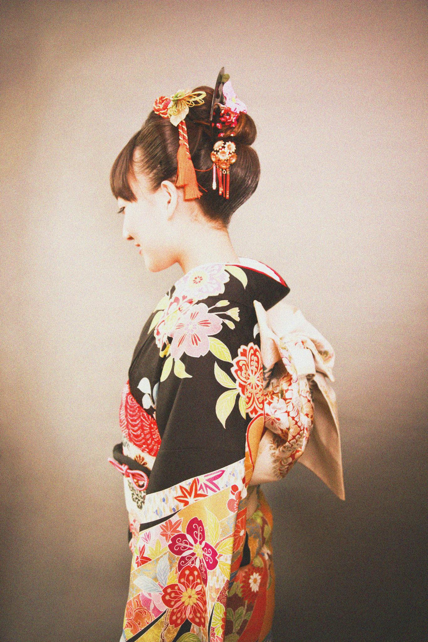 Side profile of a woman in a colorful kimono with traditional Japanese hairstyle.